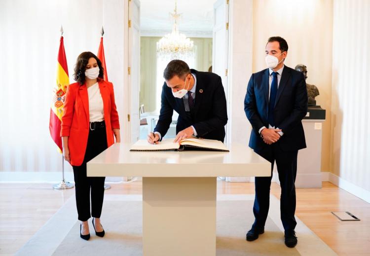 Pedro Sánchez firma en el libro de honor de la Comunidad de Madrid, ante Isabel Díaz Ayuso e Ignacio Aguado.