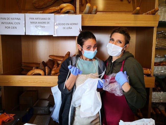 Dos dependientas de una panadería de Granada sonríen tras las mascarillas.