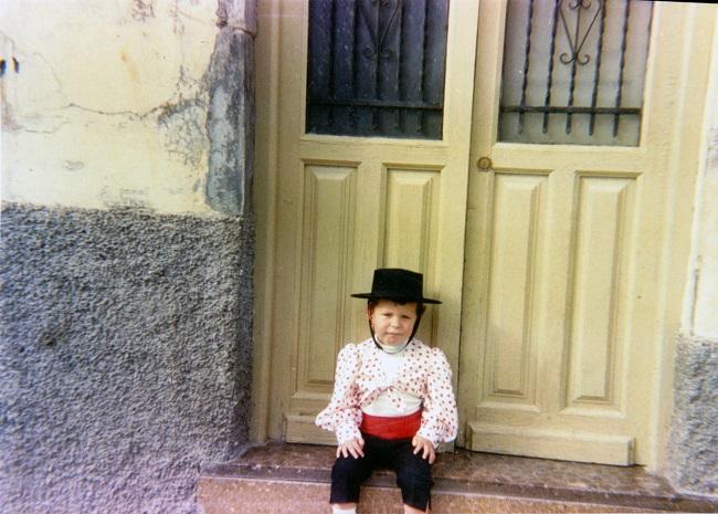 El autor, vestido de flamenco con motivo del Corpus o del Día de la Cruz, sentado en la puerta de la casa de sus abuelos, en Parrilla, nº 20 (hacia 1988-1989).