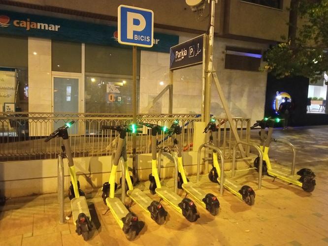 Patinetes eléctricos de alquiler en un aparcamiento para bicicletas. 