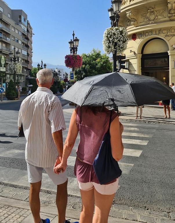 Una mujer se protege del sol con un paraguas en Puerta Real. 