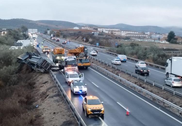Vehículo de transporte especial, volcado en la cuneta de la A-92, mientras es auxiliado. 