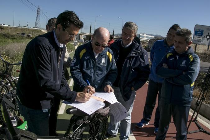 Los alcaldes firman el acuerdo en el mismo carril bici. 