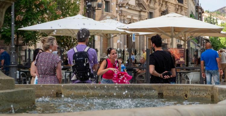 Turistas se refrescan en la fuente de Plaza Nueva.