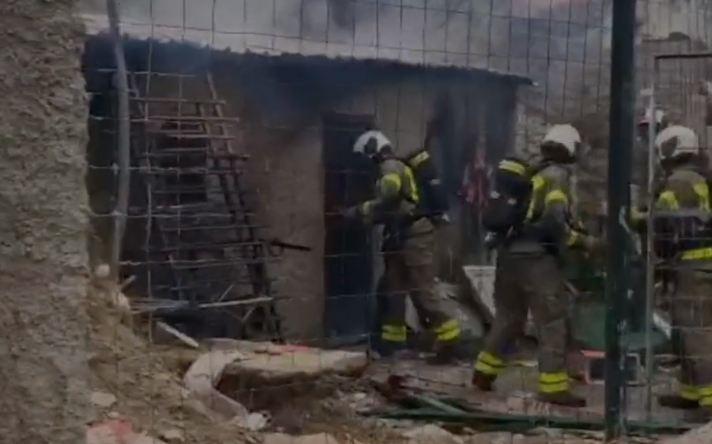 Bomberos acceden a la casa cueva incendiada.
