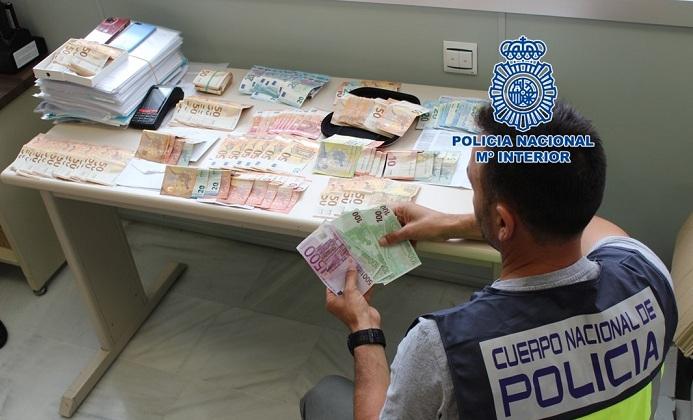 Un agente cuenta el dinero intervenido a la red delictiva, 20.000 euros. 