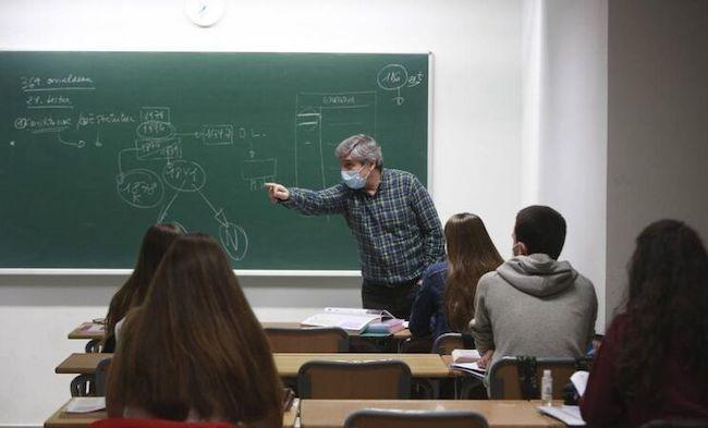 Un docente imparte una clase con mascarilla.