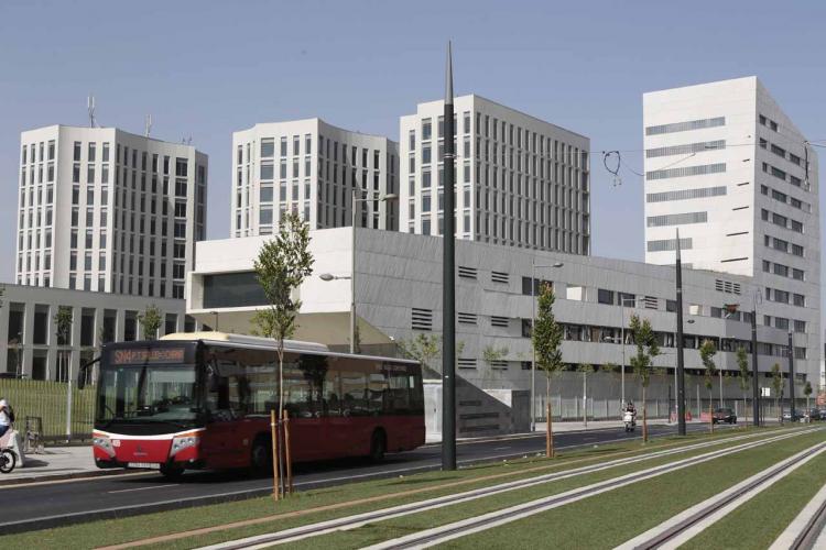 Un autobús de una línea convencional pasa junto a las vías del tren en el PTS.