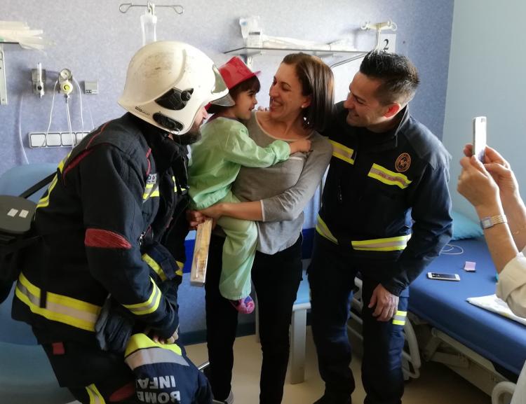 La pequeña Elena sonríe con el casco de bomberos. 