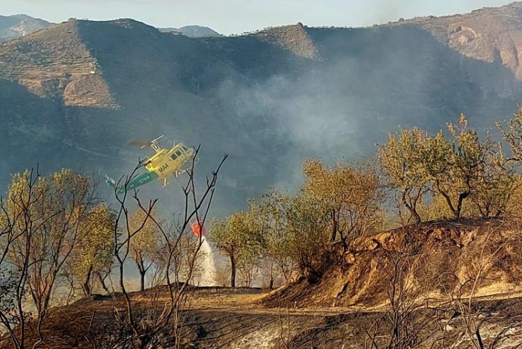 Un helicóptero descarga agua sobre el incendio de Pinos Genil.