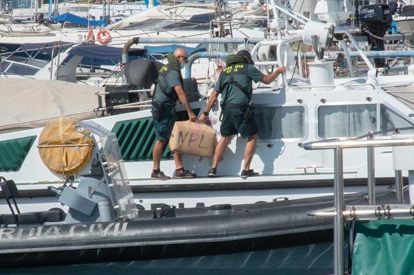 Dos agentes sacan de la embarcación el fardo de hachís.