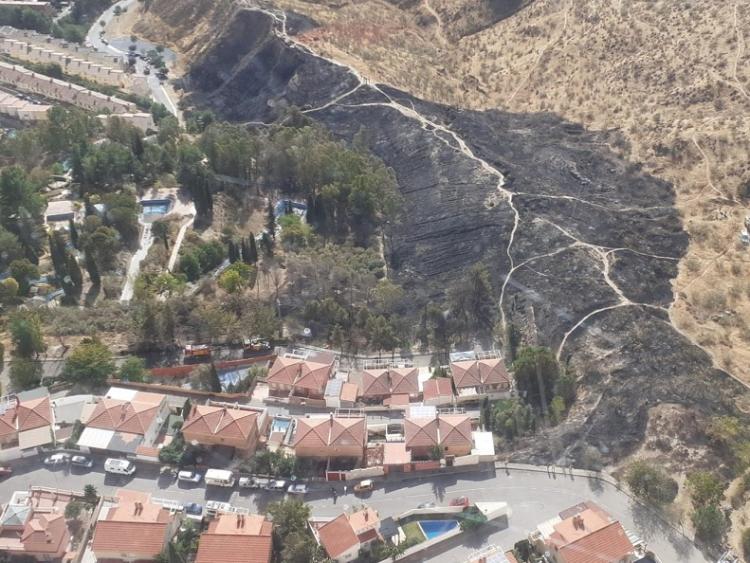 La imagen muestra parte de la zona quemada junto a una urbanización. 