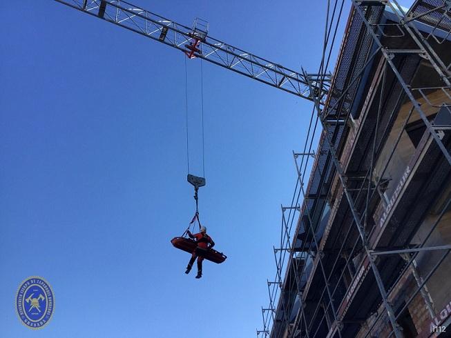 Un bombero baja al herido usando la grúa de la obra donde estaba trabajando.