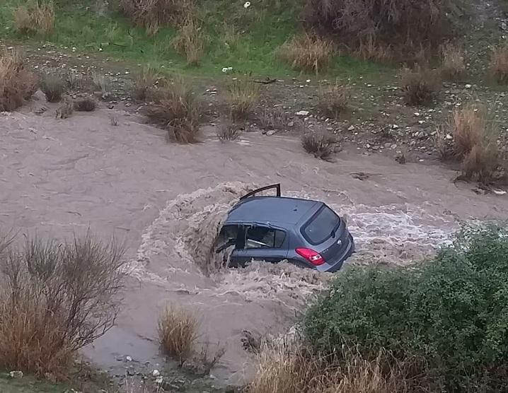 Uno de los vehículos arrastrado por la corriente del río Dílar, ya detenido al quedar encallado. 