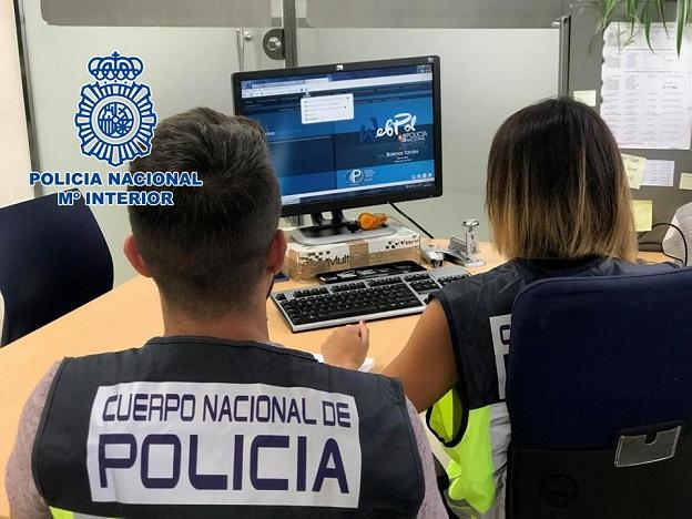 Agentes examinan material en un ordenador. 