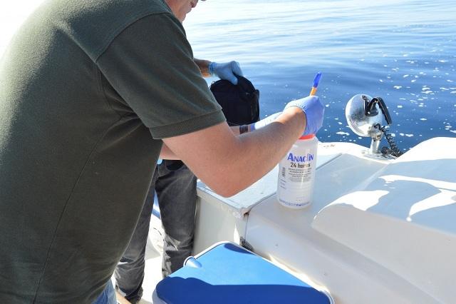 Un agente toma muestras del agua. 