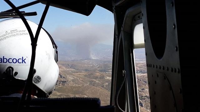 Un helicóptero se dirige a la zona del fuego, al fondo.