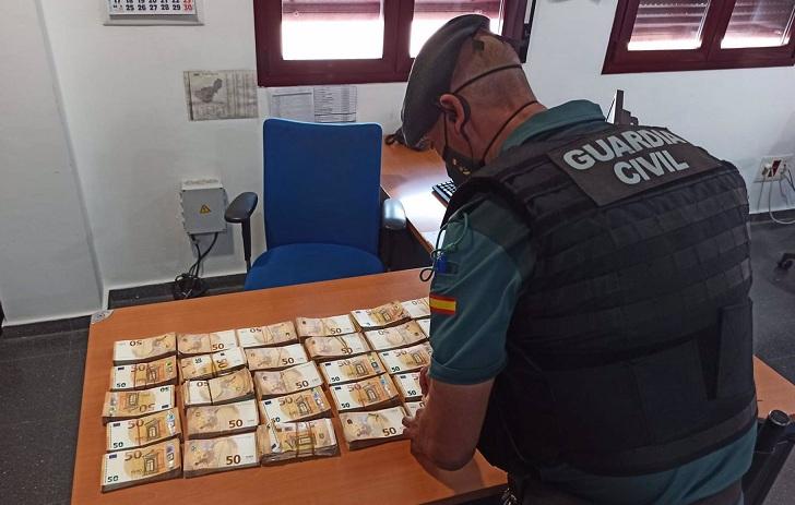 Un agente, junto al dinero requisado. 