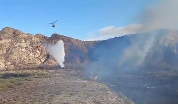 El helicóptero descarga agua sobre la zona afectada por el fuego. 