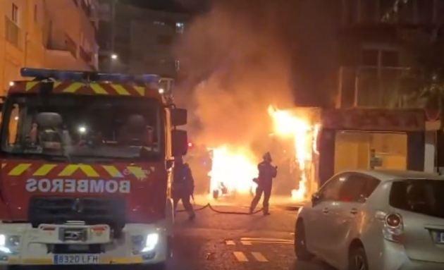 Bomberos apagan el fuego en el vehículo incendiado.