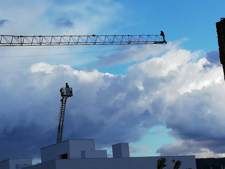 En la imagen se observa la imagen del hombre subido a la grúa y el operativo de Bomberos.