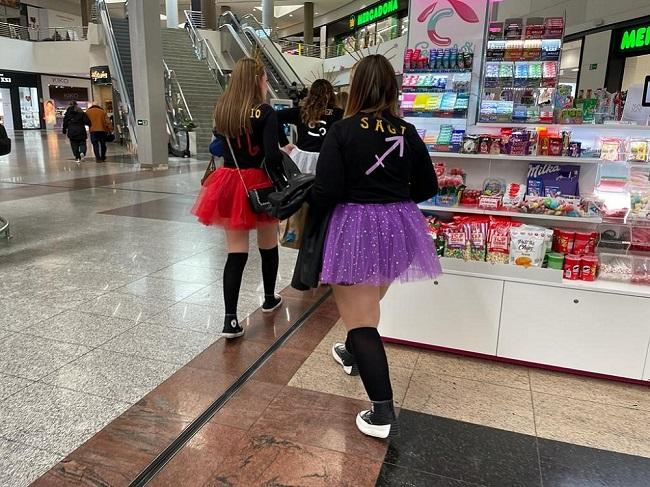 Grupo de jóvenes, en un centro comercial, disfrazadas para una celebración. 
