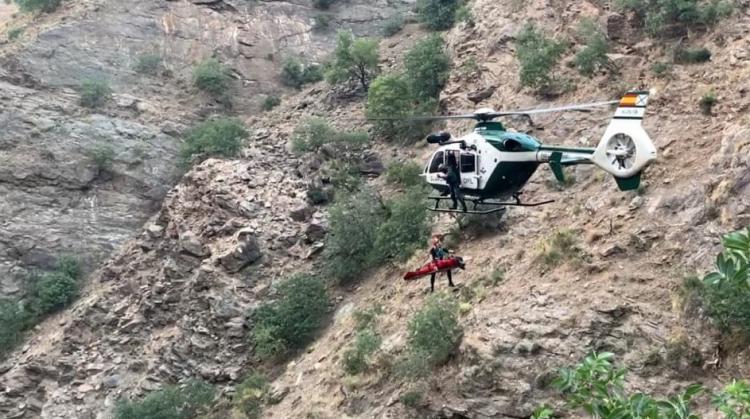 Imagen del helicóptero de la Guardia Civil en el momento de proceder al rescate de uno de los cuerpos.