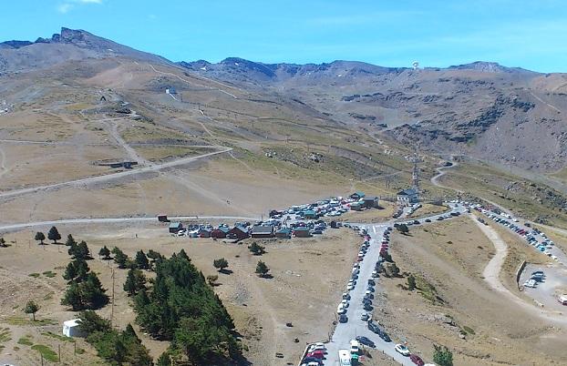 Vista de la Hoya de la Mora, repleta de vehículos, con el Veleta al fondo.