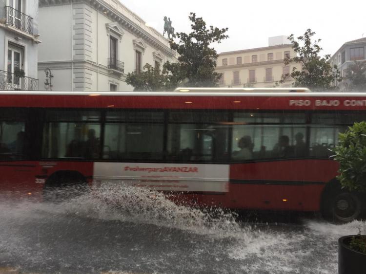 Mucha agua en Reyes Católicos al paso de un autobús urbano.