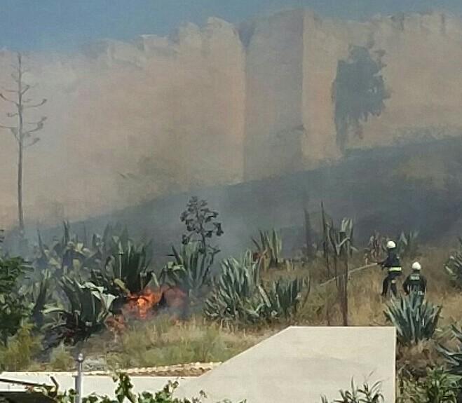 Bomberos actúan para sofocar el fuego, junto a la muralla. 