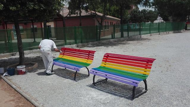 Dos de los bancos pintados con la bandera arcoíris. 