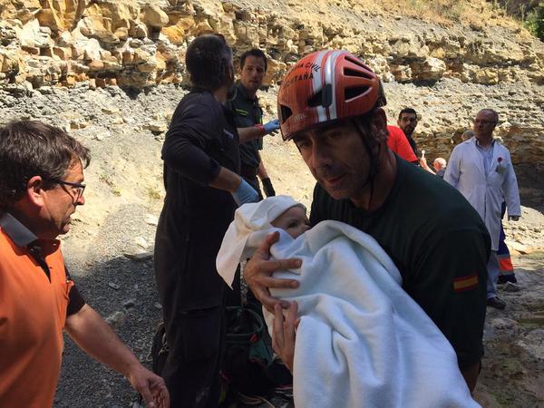 Uno de los guardias lleva en brazos al bebé, tras el rescate.