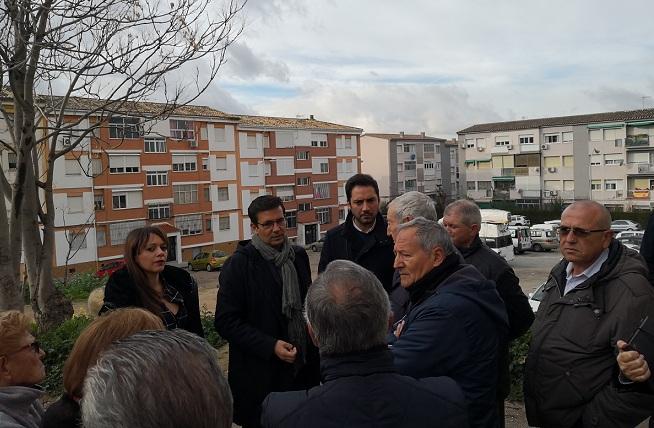 El alcalde habla con los vecinos junto a la parcela abandonada.