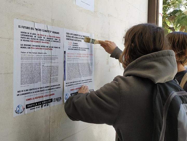 Pegada de carteles en la UGR con información científica sobre la crisis climática. 