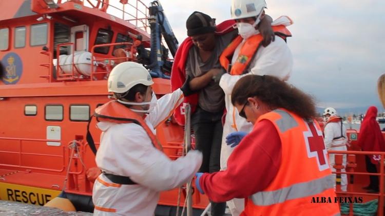 Voluntarios de Cruz Roja y miembros de Salvamento Marítimo ayudan a desembarcar a un inmigrante.
