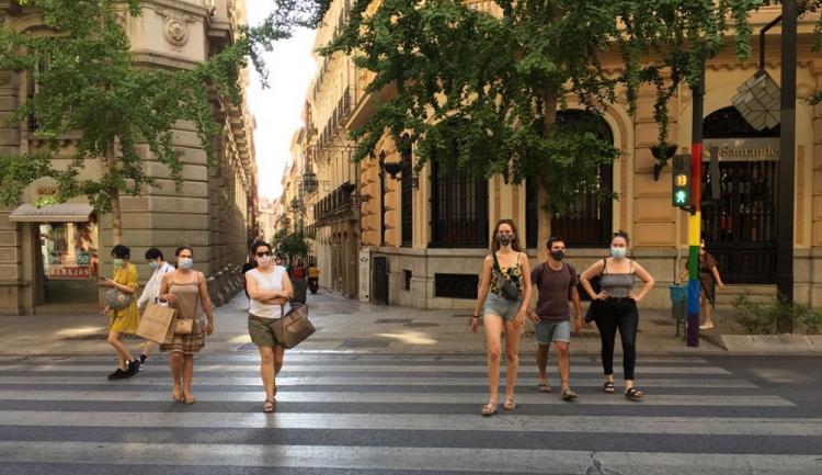 Paseantes con mascarillas cruzan un semáforo en Gran Vía.