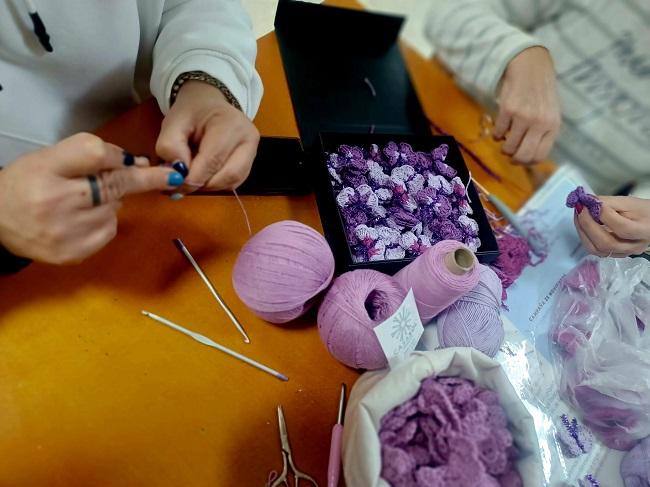 Mujeres tejiendo mariposas moradas.