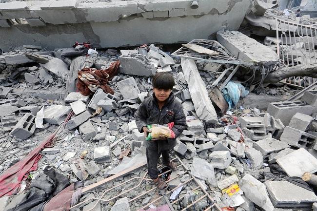 Un niño palestino con una bolsa de comida en una escuela bombardeada.