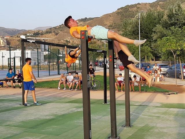 Jóvenes realizan ejercicios con barras en la nueva zona de gimnasia. 