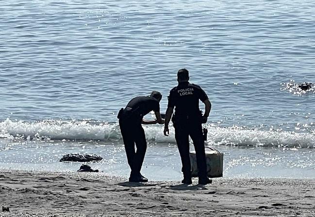 Dos agentes de la Policía Local de Almuñécar fotografían el fardo localizado.