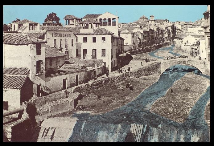 Postal coloreada del Darro descubierto en 1900; en primer término, presa de la Acequia Gorda; en el centro, el Puente de la Virgen, la parte trasera del Rastro (dcha.) y el malecón de la Acera del Darro discurriendo por la izquierda. 