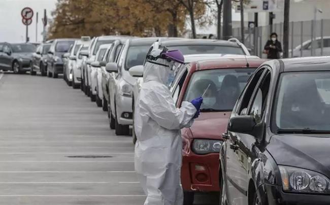 Un sanitario realiza una prueba PCR a una persona desde su vehículo para la detección del coronavirus.