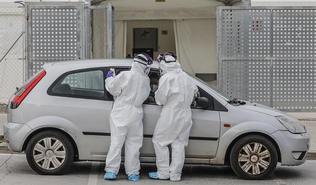 Dos sanitarios realizan una prueba PCR a una persona desde su vehículo en una imagen de archivo.