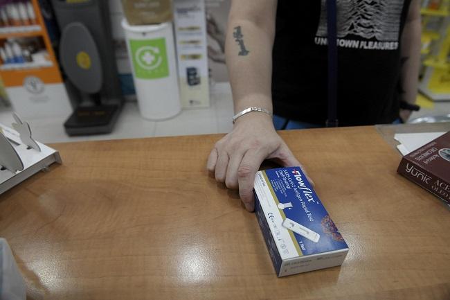 Un cliente enseña un test de antígenos de detección del COVID-19 en una farmacia, foto de archivo.