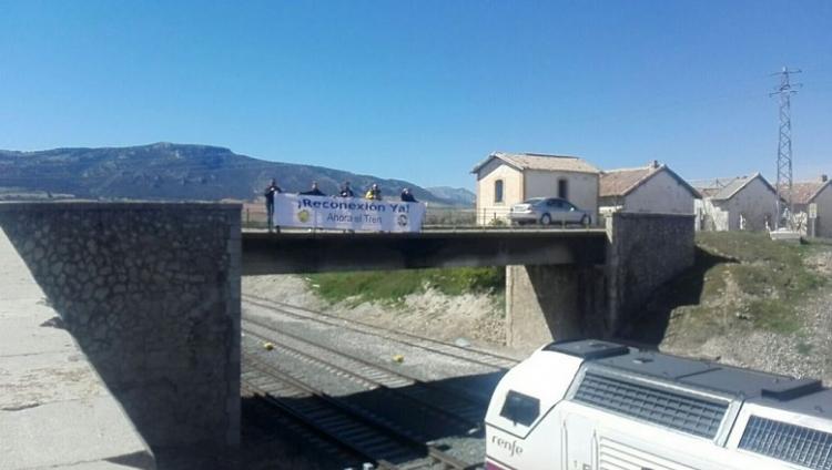 Pancarta pidiendo la reconexión al paso de un tren por Moreda.