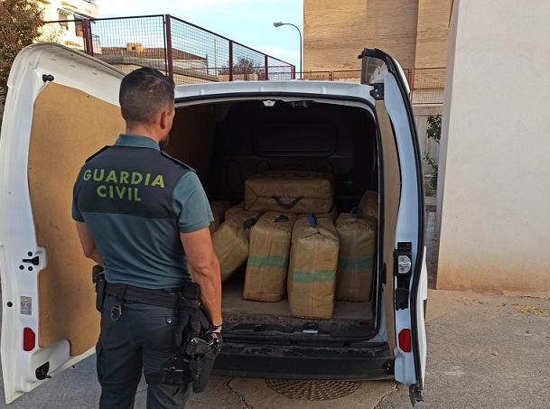 Un agente, junto a la furgoneta cargada de fardos de hachís. 