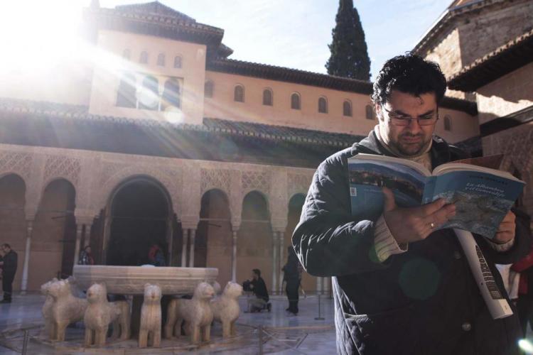 Un turista ojea una guía en el Patio de los Leones.