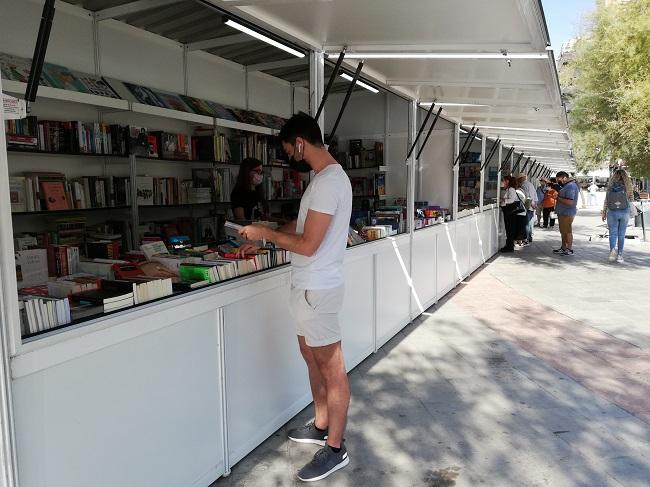 Un lector ojea un libro en una caseta en Puerta Real.