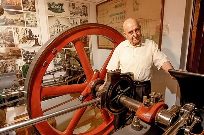 Miguel posa en su casa junto a una máquina de vapor restaurada por él hace años. 