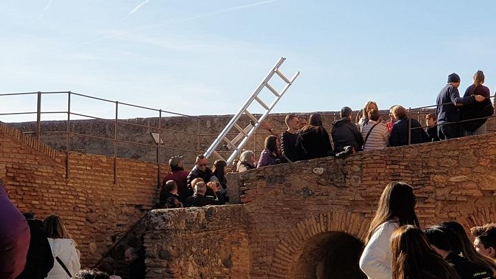 Un empleado de la Alhambra lleva una escalera para arreglar la cuerda de la campana.